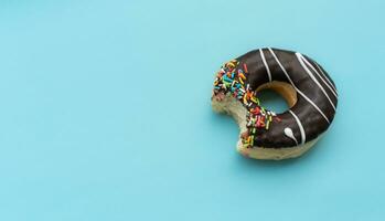 Messy chocolate doughnut isolated on blue background, after some edits. photo