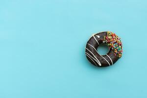 Messy chocolate doughnut isolated on blue background, after some edits. photo