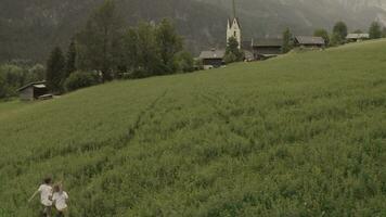 zwei Menschen Gehen durch ein Feld mit ein Kirche im das Hintergrund video