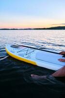 Male legs on a paddle board. photo