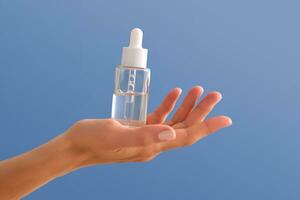 Serum with a pipette in female hands on a blue background. photo