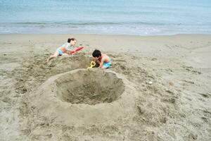 Children dig a hole in the sand on the seashore. photo