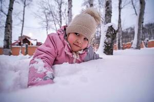 un niña obras de teatro en profundo nieve en el patio trasero. foto