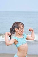 un niña muestra su fuerza después nadar. foto