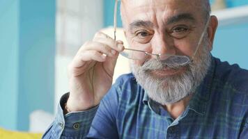 Happy old man taking off his glasses and looking at camera. video