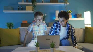 Two teenage boys watching scary videos on laptop.