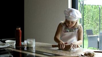 un joven niña en un cocinero sombrero haciendo masa video