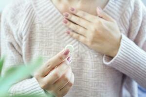 woman having problem with heartburn from acid reflux disease hand taking antacid medicine for GERD treatment photo