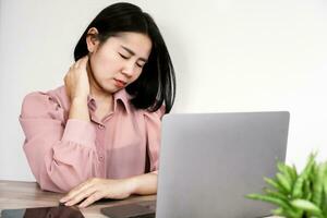 Asian business woman suffering from neck and shoulder pain, office syndrome sitting too long on chair working on computer photo