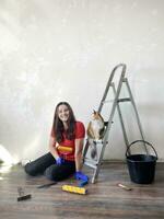 Pleased young woman enjoying renovation time at home with cat. Repair and remodeling concept photo