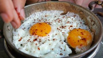 putting chili flakes on Fried eggs in the plate video