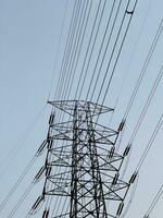 High voltage electric tower against a clear blue sky. Tall, steel pole of power lines against the sky. photo