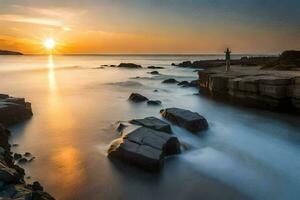 a man standing on rocks at the beach at sunset. AI-Generated photo
