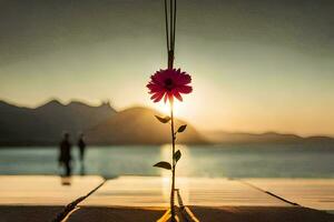 a flower is hanging from a rope over the water. AI-Generated photo