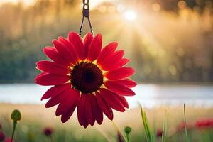 a red flower hanging from a chain in front of a lake. AI-Generated photo