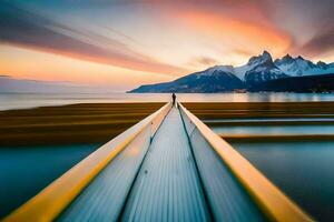 a man is standing on a long wooden dock in front of a mountain. AI-Generated photo