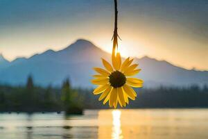 a sunflower hanging from a tree in front of a lake. AI-Generated photo