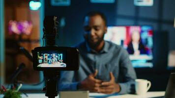 Content creator doing technology review of wireless portable speaker for online platforms channel. African american influencer presenting music playing device to his audience video