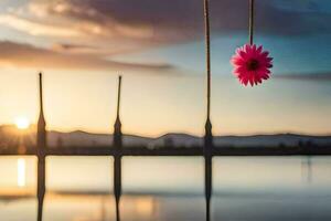 a pink flower hanging from a rope over a body of water. AI-Generated photo