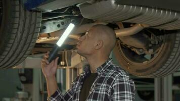 Young African man examining his automobile at the workshop video