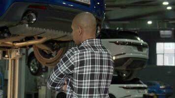 Cheerful African man smiling to the camera standing at cars workshop video