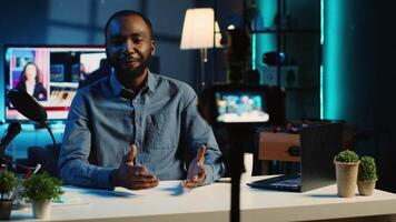 Smiling content creator using professional recording devices in cozy studio to film video intro for online streaming platforms. Influencer greets fanbase, doing monologue about topic