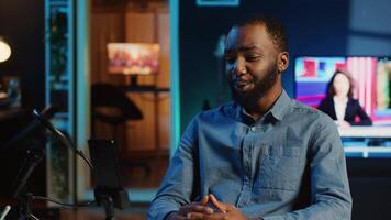 Content creator in dimly lit home studio using cellphone camera to film video for online streaming platforms. Influencer hosts q a session with audience using mobile phone