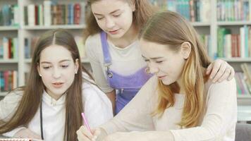 três adolescente meninas estudando juntos às a biblioteca video