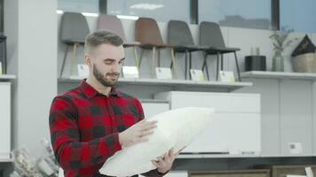 Handsome young man choosing new pillow to buy at furnishings store video