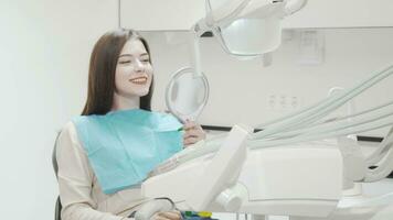 heiter jung Frau lächelnd zu das Kamera Sitzung im Dental Stuhl video