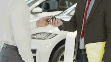 Cropped shot of a man receiving car keys from salesman and shaking hands video