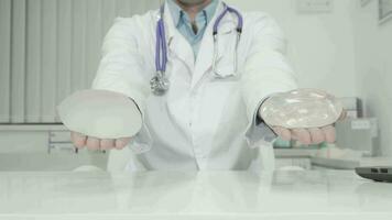 Plastic surgeon holding out silicone breast implants to the camera video