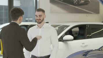 contento joven hombre recepción coche llaves a su nuevo auto desde el vendedor video