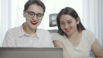 Two female freelancers using laptop while working together video