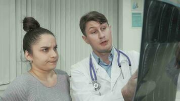 Experienced doctor showing x-ray scan to female patient video