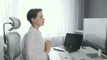 Young businesswoman stretching her back while working on a computer video