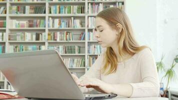 encantador adolescente menina trabalhando em dela computador às a biblioteca video