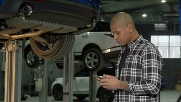 Handsome African man using smart phone at the garage video
