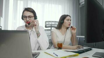 Two female call center agents working on their computers video