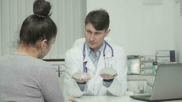 Plastic surgeon showing types of silicone breast implants to the patient video