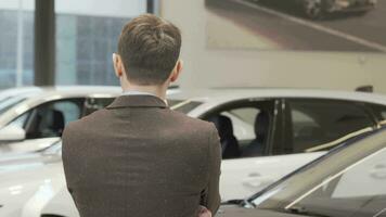 Happy mature man smiling to the camera while choosing car to buy video