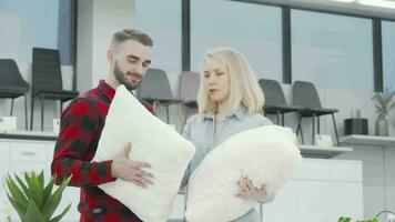 Happy couple smiling to the camera while shopping for pillows at furnishings store video