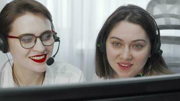 Cropped shot of two female call center operators with headsets using computer video