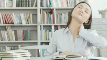 giovane attraente femmina alunno allungamento sua indietro mentre studiando a il biblioteca video