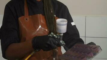 Cheerful female chef using airbrush decorating chocolate mold video