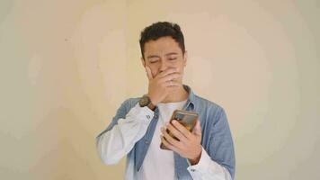 Young Indonesian man with denim style surprised when check the smartphone.  The footage is suitable to use for man expression and lifestyle content media. video