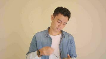 Jeune indonésien homme avec denim style Ecoutez la musique portant écouteur. le métrage est adapté à utilisation pour homme expression et mode de vie contenu médias. video