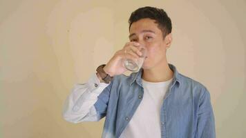 jung indonesisch Mann mit Denim Stil war Trinken Wasser. das Aufnahmen ist geeignet zu verwenden zum Mann Ausdruck und Gesundheit Leben Stil. video