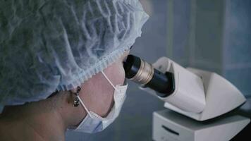 Doctor in hospital laboratory looking through microscope video