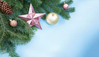 Pink shiny star, balls and cones on pine and spruce branches on blue background with place for text. Christmas, New Year. Copy space photo